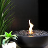 A close-up view of the EcoSmart Fire Mix 850 graphite fire pit, showcasing the sleek black fire bowl filled with reflective fire glass. The vibrant flames flicker elegantly, making this luxury fire pit a perfect addition to modern outdoor fire spaces and contemporary patios.