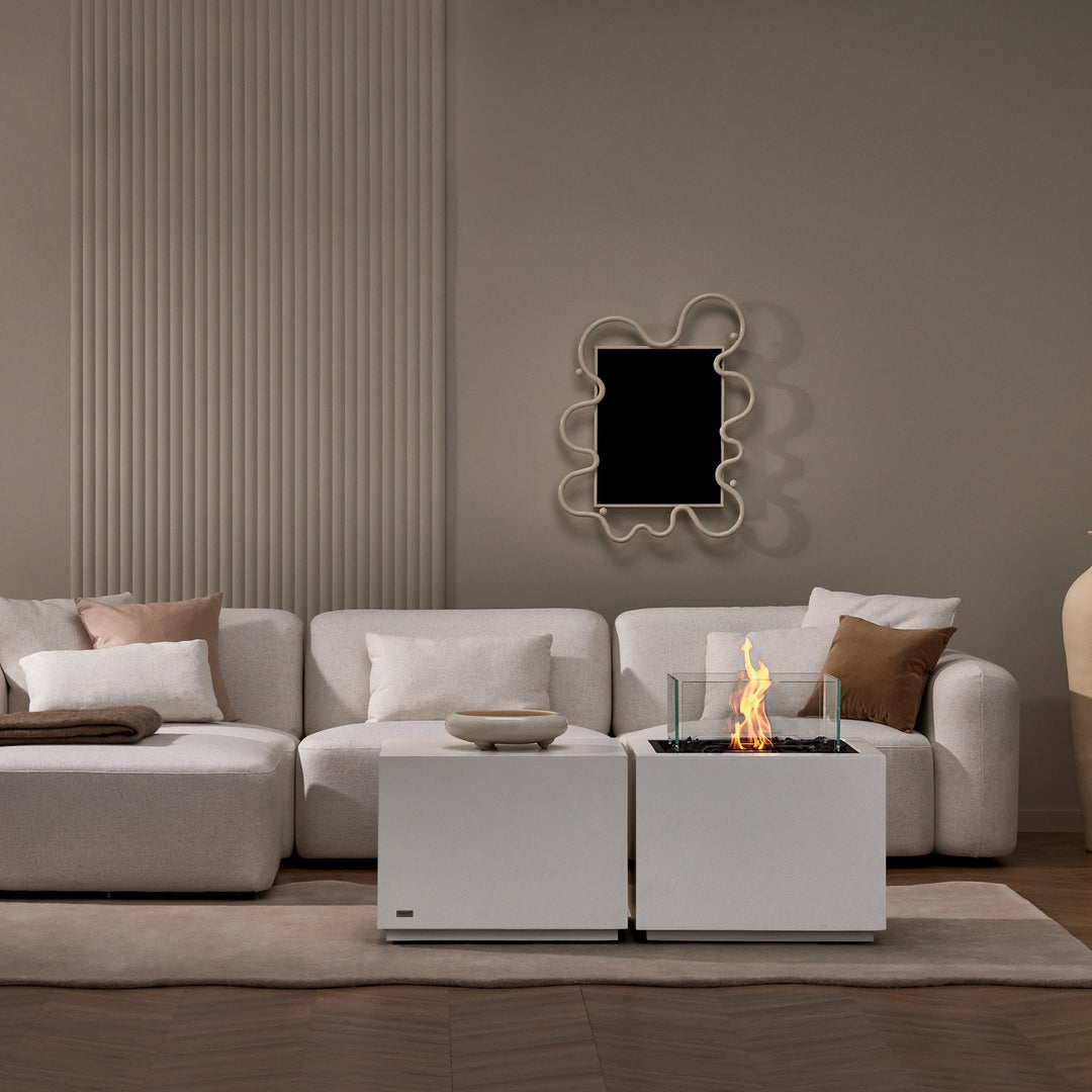 The EcoSmart Fire Sidecar 24 enhances the contemporary feel of this living room, featuring a sleek white fire pit with a clear glass wind guard. The stylish fire element adds warmth to the space, perfect for relaxing with family and friends. Its clean, square shape fits perfectly within a chic, modern home, adding both style and comfort to your dÃ©cor.
