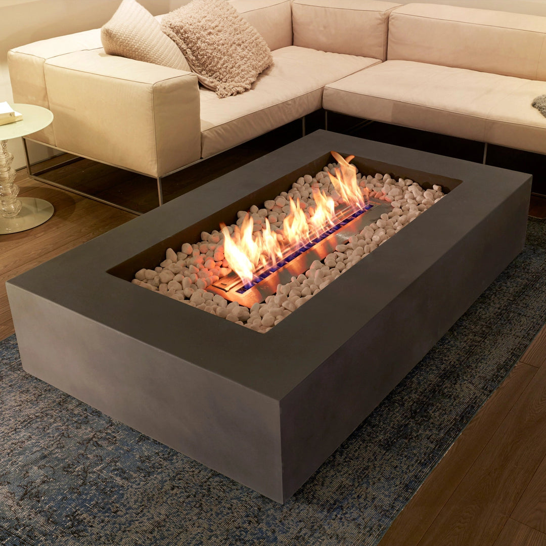 A contemporary indoor living room with a centrally placed EcoSmart Fire Wharf 50, surrounded by a neutral-toned sectional sofa. The concrete fire pit with white fire stones adds a modern yet cozy touch, seamlessly integrating an indoor fire feature with stylish home dÃ©cor.