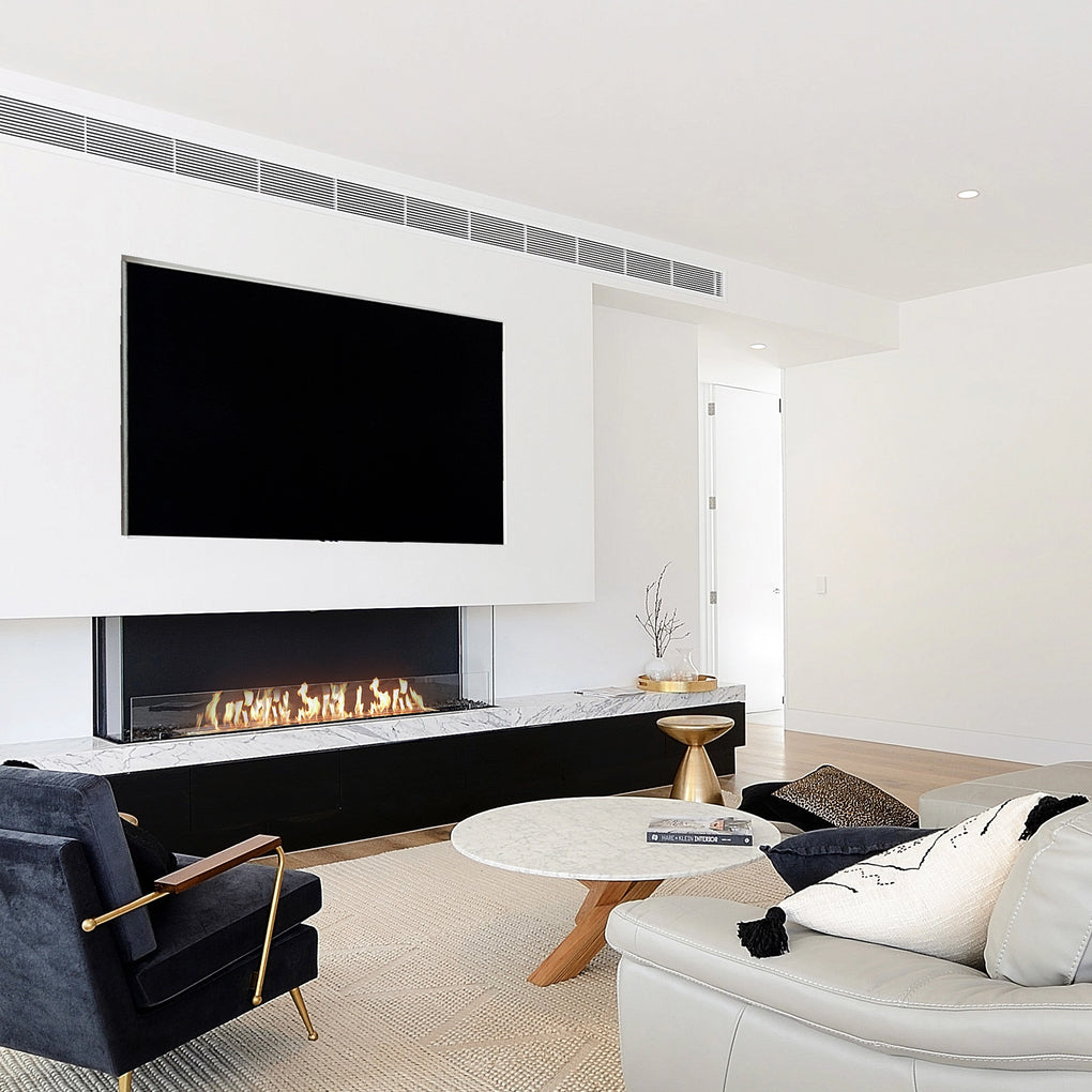 Contemporary minimalist living room with a linear fireplace featuring a marble surround, wall-mounted flat-screen TV, a black armchair with gold armrests, a round marble coffee table, and a sofa with textured cushions, creating a luxurious and elegant space