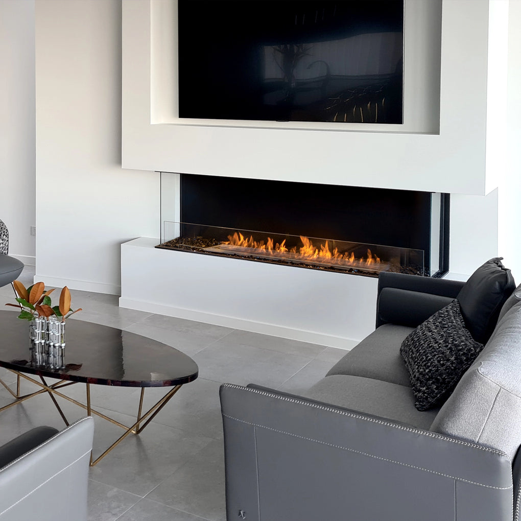 Contemporary living room with a modern linear fireplace installed below a wall-mounted flat-screen TV, surrounded by minimalist decor and neutral color tones, creating a sleek and sophisticated atmosphere