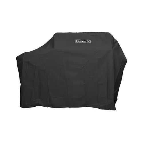 a black vinyl BBQ grill cover with the Fire magic logo printed on the front is draped over a portable BBQ grill and presented on a white background