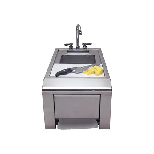 A stainless steel outdoor kitchen built-in BBQ kitchen sink complete with cutting board and paper towel rack underneath that's designed for the outside elements is presented on a white background