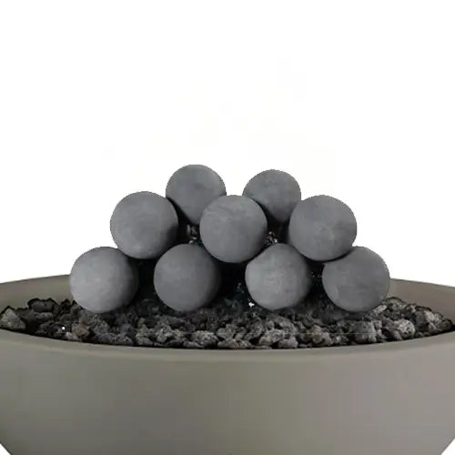 fire balls are featured in a pile on top of a gray round fire pit filled with lava rock pieces