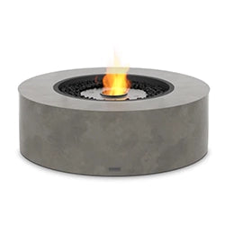 Modern round ethanol fire pit with a concrete finish, featuring a central flame surrounded by black fire glass stones, ideal for stylish outdoor living spaces