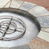 Stainless steel fire pit burner pan and ring assembly installed inside a stone fire pit with a form-fitting ledge securing the pan in place