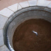 Form-fitting ledge installed inside a circular fire pit structure with visible screws securing the ledge in place around the inner edge of the stonework