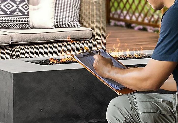 Professional inspecting a modern concrete fire pit in a stylish outdoor setting, emphasizing installation, maintenance, and quality assurance.