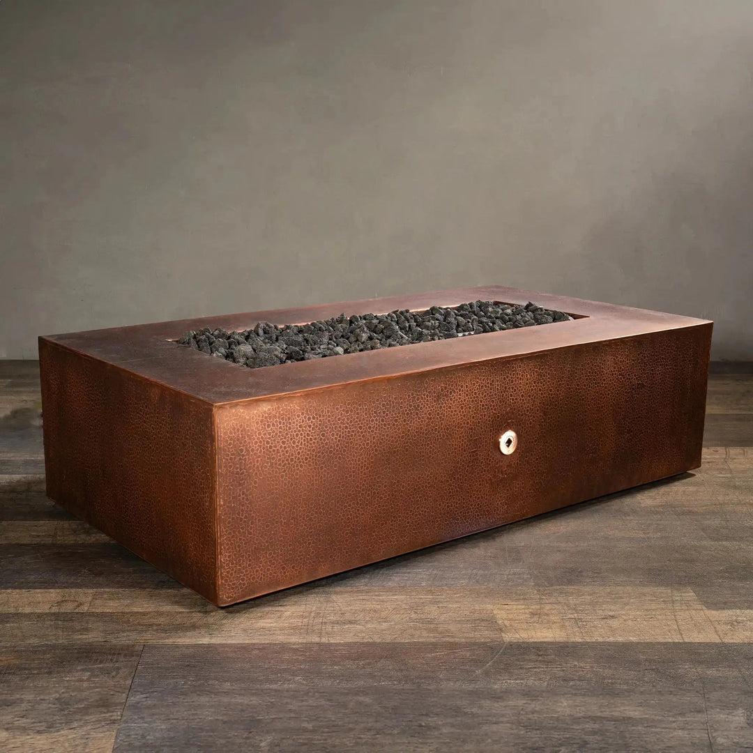 Angled view of the Gravity Moreno 60x32 rectangular copper fire pit by Starfire Designs, showcasing the sleek, handcrafted copper finish with lava rocks, ideal for upscale outdoor settings
