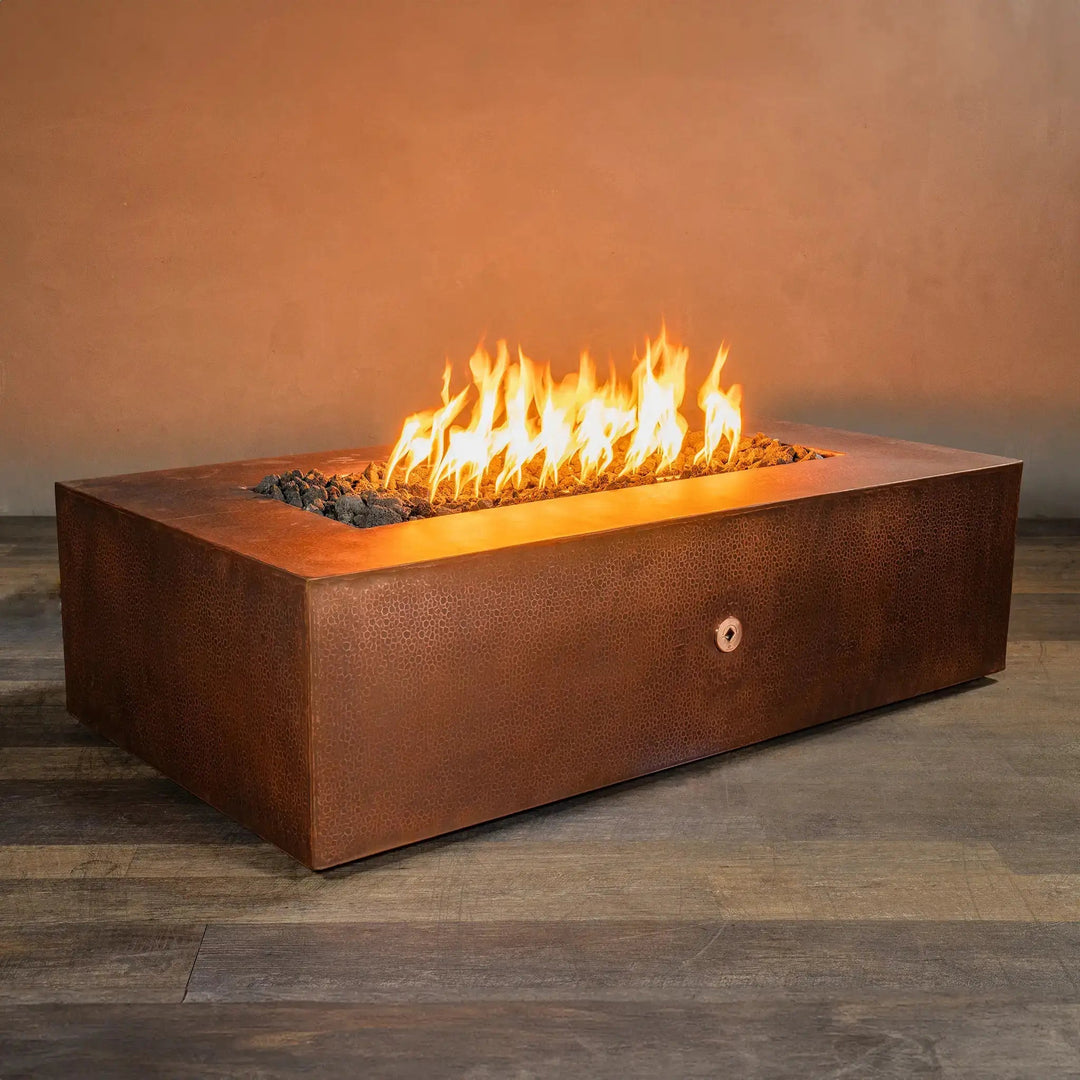 Angled view of the Gravity Moreno 60x32 rectangular copper fire pit by Starfire Designs, showcasing its hammered copper finish and wide burning area, ideal for creating a warm and inviting outdoor patio ambiance
