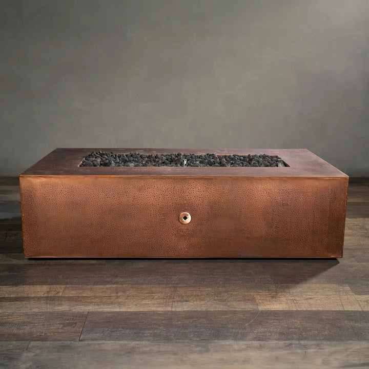 Side view of the Gravity Moreno 60x32 rectangular copper fire pit by Starfire Designs, showcasing its elegant handcrafted copper finish with lava rocks, ideal for enhancing outdoor spaces