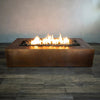 Gravity Moreno 72x38 copper fire pit by Starfire Designs, displaying a wide rectangular design with an active flame surrounded by black lava rocks, ideal for upscale outdoor settings