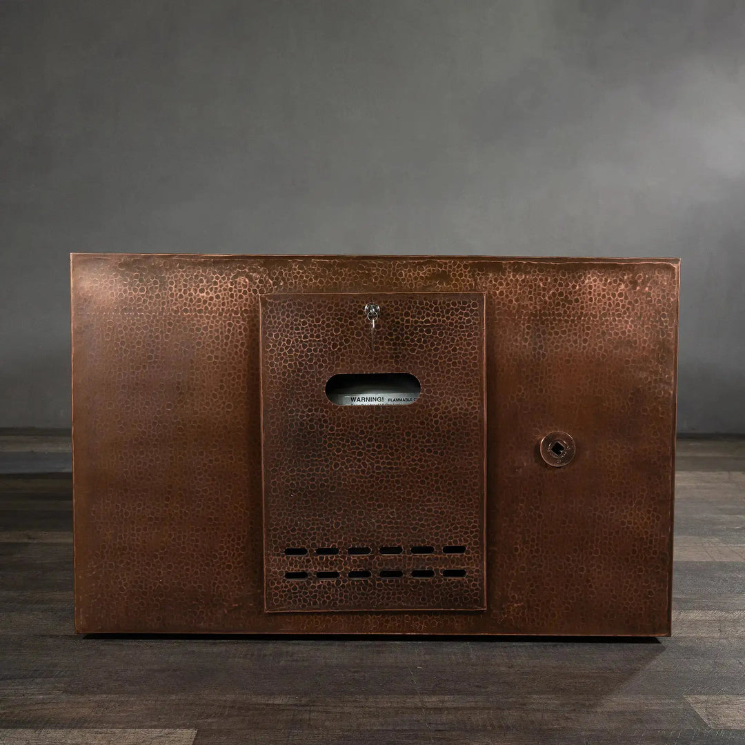 Front view of the Gravity Moreno 72x38 copper fire pit by Starfire Designs, highlighting the hidden propane tank access panel with a hammered copper finish
