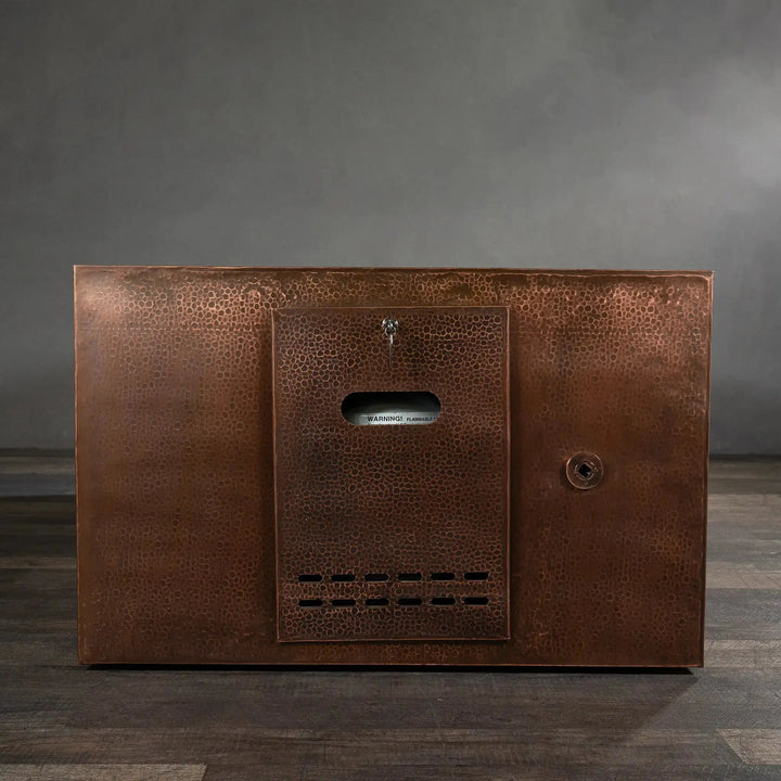 Front view of the Gravity Moreno 72x38 copper fire pit by Starfire Designs, highlighting the hidden propane tank access panel with a hammered copper finish