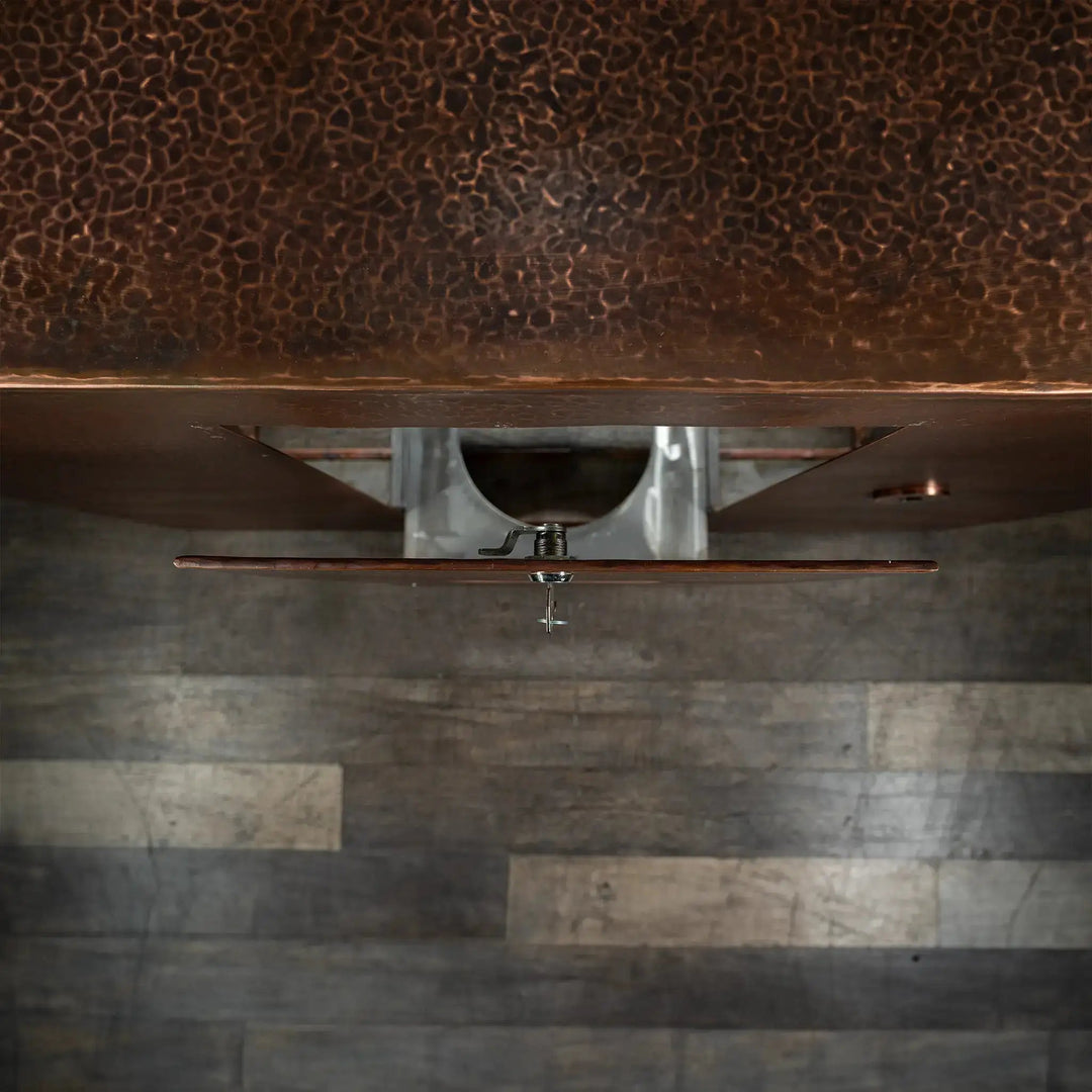 Top view of the Gravity Moreno copper fire pit by Starfire Designs showing the detail of the opened propane tank door with hammered copper finish