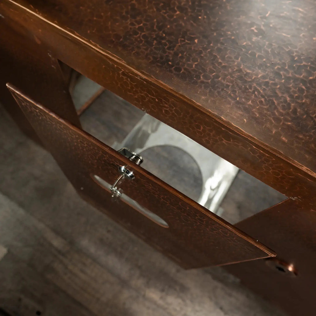 Top view of the Gravity Moreno copper fire pit by Starfire Designs showing the opened propane tank door with a hammered copper finish