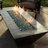 Closeup of Largo Moreno 60-inch x 26-inch Rectangle Copper Fire Pit, featuring a vibrant flame and reflective fire glass on a hand-hammered copper finish