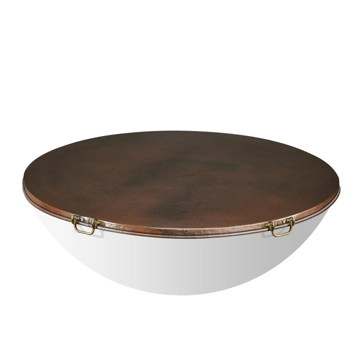 Moreno 54-inch round copper fire pit lid by Starfire Designs, displayed on a white background. Featuring a hammered copper finish and two brass handles, this lid provides protection and adds a touch of luxury to outdoor fire pits and fire tables. Perfect for covering large fire bowls in high-end backyard and patio settings