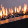 Close-up view of medium-sized volcanic lava rocks in a fire pit. The 2-3 inch black volcanic stones provide excellent heat distribution and add a natural, rustic charm to outdoor fire features. Perfect for enhancing any outdoor fire pit.
