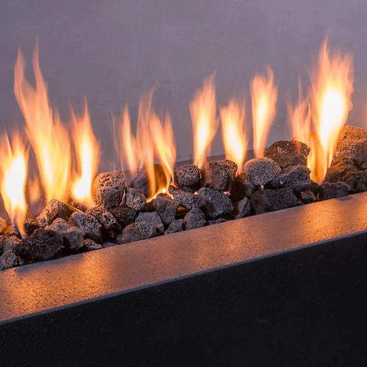 Close-up view of medium-sized volcanic lava rocks in a fire pit. The 2-3 inch black volcanic stones provide excellent heat distribution and add a natural, rustic charm to outdoor fire features. Perfect for enhancing any outdoor fire pit.