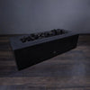 Medium volcanic lava rocks resting in a modern fire pit without flames. The 2-3 inch black porous stones are perfect for retaining heat and maintaining a rugged, natural outdoor aesthetic. Ideal for use in fire pits and outdoor fireplaces