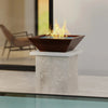 Plaza Moreno 29-inch square copper fire bowl on a modern outdoor pedestal, showcasing a natural gas flame with blue fire glass, ideal for contemporary patio designs