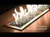 Vibrant Pacific Blue 1/4" Reflective Fire Glass from American Fire Products glowing beneath bright flames in a modern fire feature—its rich ocean-blue tones and mirrored surfaces create a striking visual contrast, perfect for enhancing outdoor ambiance with color and shine.