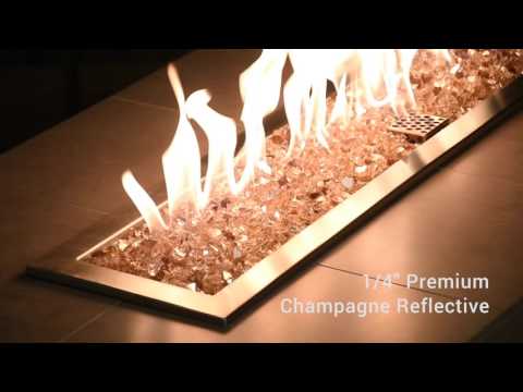 Outdoor fire pit filled with 1/4" Champagne Reflective Fire Glass from American Fire Products, glowing elegantly under tall golden flames—perfectly blending luxurious ambiance and modern outdoor design.