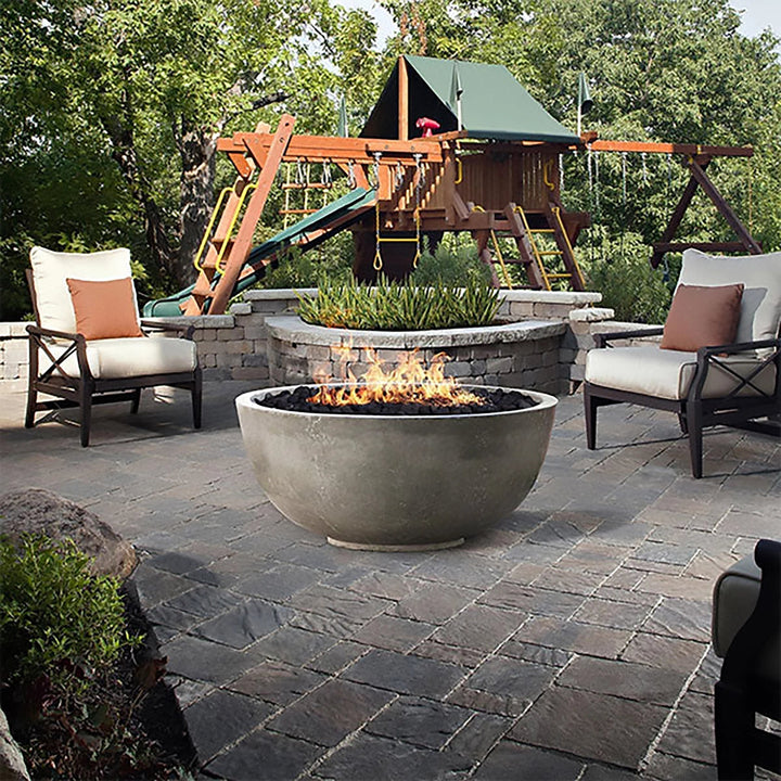 Prism Hardscapes Moderno 1 Gas Fire Bowl situated in a beautifully landscaped garden patio with surrounding seating. This modern fire pit provides warmth and elegance to outdoor gatherings, making it a perfect addition to any backyard or commercial outdoor space. Designed for both residential and luxury commercial environments.