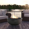 Prism Hardscapes Moderno 1 Gas Fire Bowl positioned on a lakeside deck with comfortable outdoor seating, featuring a warm flame and lava rock filling. This stylish round gas fire pit is perfect for evening relaxation by the water, offering a modern and elegant addition to your backyard or patio setting.