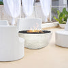 Prism Hardscapes Moderno 1 Gas Fire Bowl showcased in a chic outdoor lounge with white furniture. The fire pit provides a stylish contrast with its natural concrete finish and black lava rock, making it the focal point for a modern patio or outdoor space. A perfect solution for those looking to add warmth and sophistication to their backyard or commercial settings