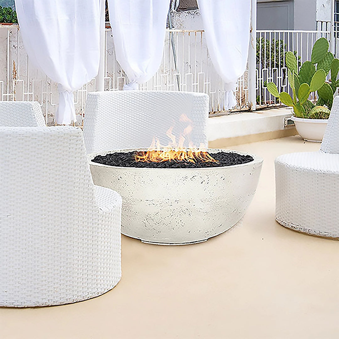 Prism Hardscapes Moderno 1 Gas Fire Bowl showcased in a chic outdoor lounge with white furniture. The fire pit provides a stylish contrast with its natural concrete finish and black lava rock, making it the focal point for a modern patio or outdoor space. A perfect solution for those looking to add warmth and sophistication to their backyard or commercial settings