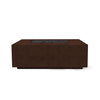 The Prism Hardscapes Portos 58" Propane Fire Table in a cafe finish is showcased in a stylish outdoor setting. This rectangular fire table features a smooth surface with a warm cafe brown color, making it a perfect centerpiece for modern patios. Ideal for outdoor fire pit enthusiasts looking for a durable and contemporary design, the table includes lava rock for a complete fire feature. Suitable for both commercial fire pit settings and large backyard fire pits.