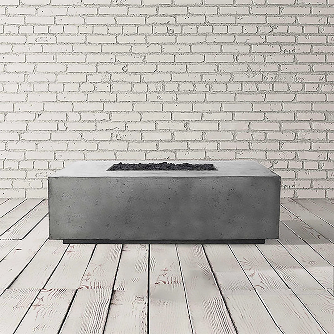 The Prism Hardscapes Portos 68 Propane Fire Table in pewter finish, set in a studio environment with a white brick wall backdrop. The fire table’s rectangular design and neutral pewter tone make it a sophisticated choice for modern outdoor spaces. Its durable concrete construction ensures longevity, while its sleek surface complements contemporary patio furniture. This fire table is perfect for outdoor entertaining and creating a cozy, inviting atmosphere. 