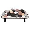 Rasmussen vented fire stones in a calico color mix, stacked on a metal grate. These assorted stones are ideal for vented fireplaces, bringing a colorful and dynamic visual appeal to any fireplace or outdoor fire pit.