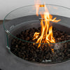 Detailed view of the Starfire Designs Beton 42 Inch Graphite Round Concrete Natural Gas Fire Pit with a vibrant flame contained by a tempered glass wind guard, accentuating the modern design and safety features for outdoor heating.
