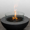 The Starfire Designs Beton 42 Inch Graphite Round Concrete Natural Gas Fire Pit with a glowing flame surrounded by a tempered glass wind guard, combining safety, modern aesthetics, and optimal heat output for outdoor gatherings.