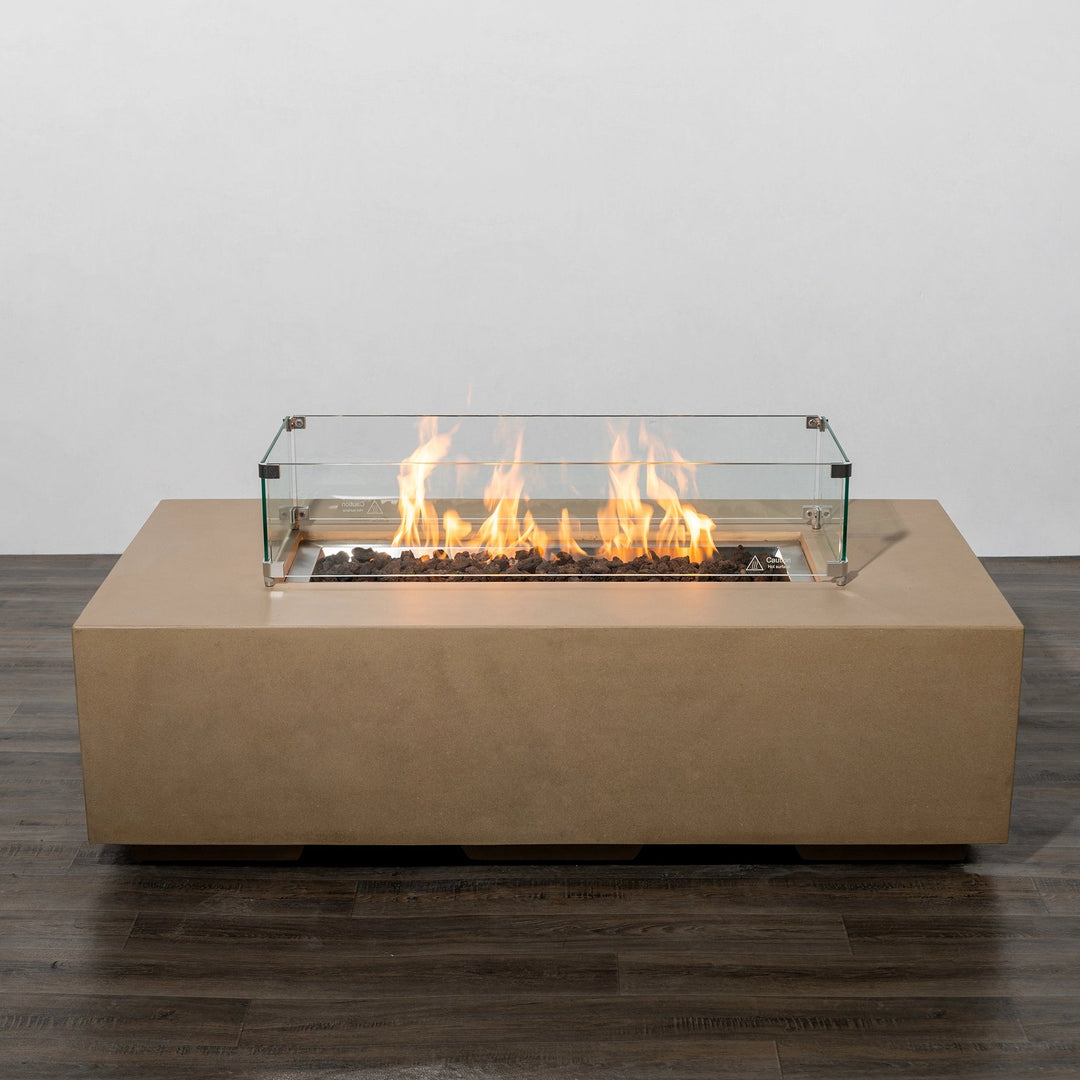 Starfire Designs Beton 55-inch sand rectangle gas fire pit lit with bright flames enclosed by a glass wind guard. The fire pit creates a stunning focal point, combining warmth and style for outdoor living spaces.