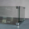 Close-up view of the Starfire Designs Beton Rectangle Glass Wind Guard, highlighting the sturdy corner construction and caution label for hot surfaces