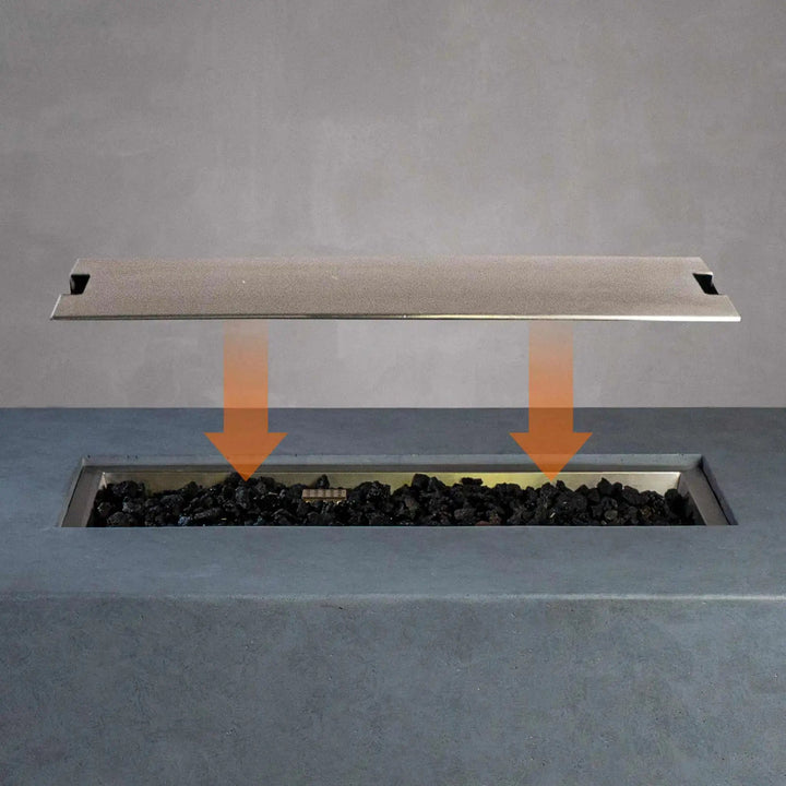 Installation guide showing how to place the Starfire Designs Beton Rectangle Stainless Steel Burner Cover onto the burner of the fire pit, with arrows indicating the correct positioning