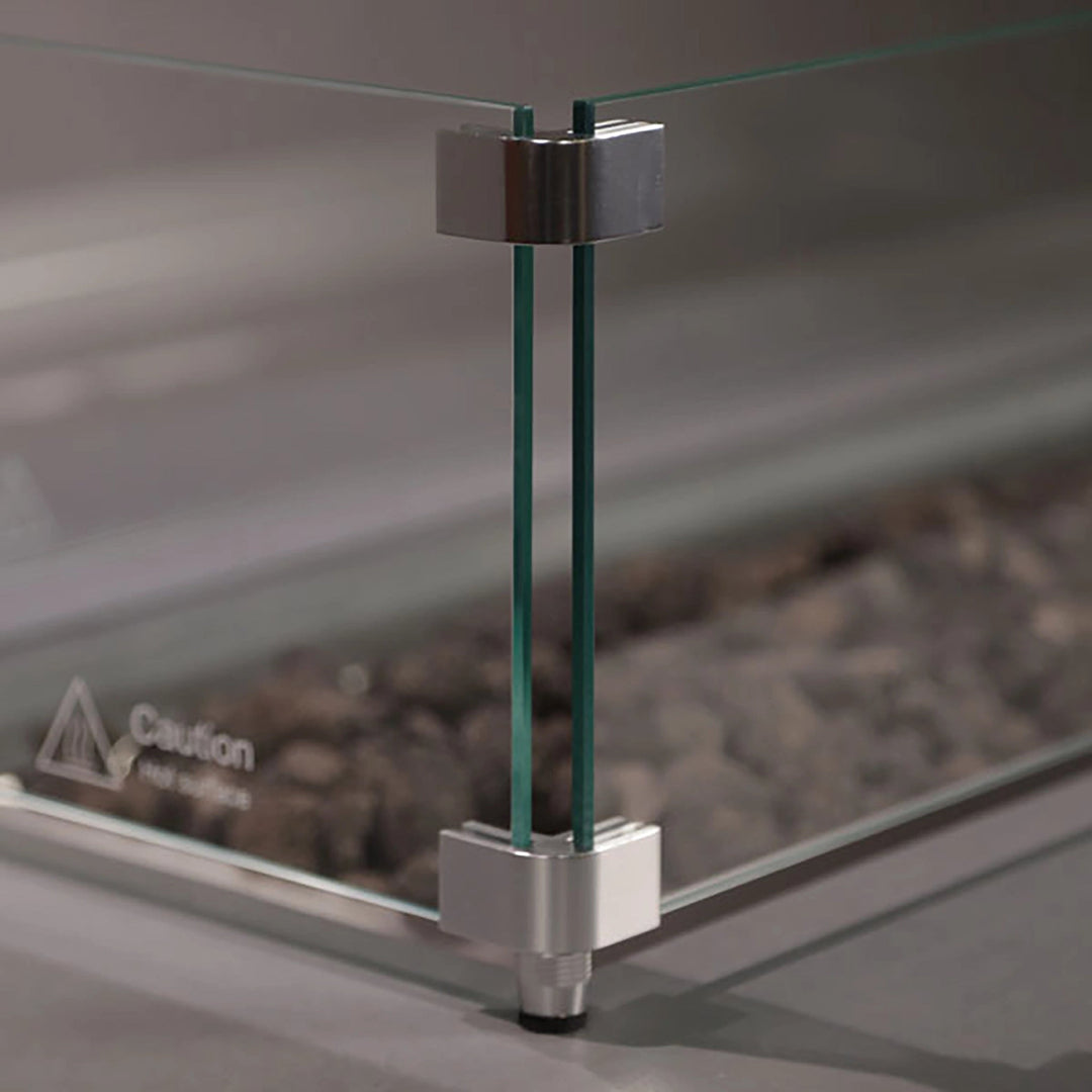 Close-up of Starfire Designs Beton Square Glass Wind Guard corner detailing. Durable tempered glass panels held by silver brackets ensure stability and safety. Ideal for windy environments, this accessory enhances the functionality and design of modern fire pits and tables.