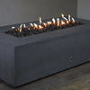 Corner view of the Starfire Designs Concrete Rustic 60" x 32" Rectangle Gravity Gas Fire Pit in Graphite. The durable concrete construction and graphite color give this fire pit a timeless, modern look, making it the perfect addition to outdoor living spaces