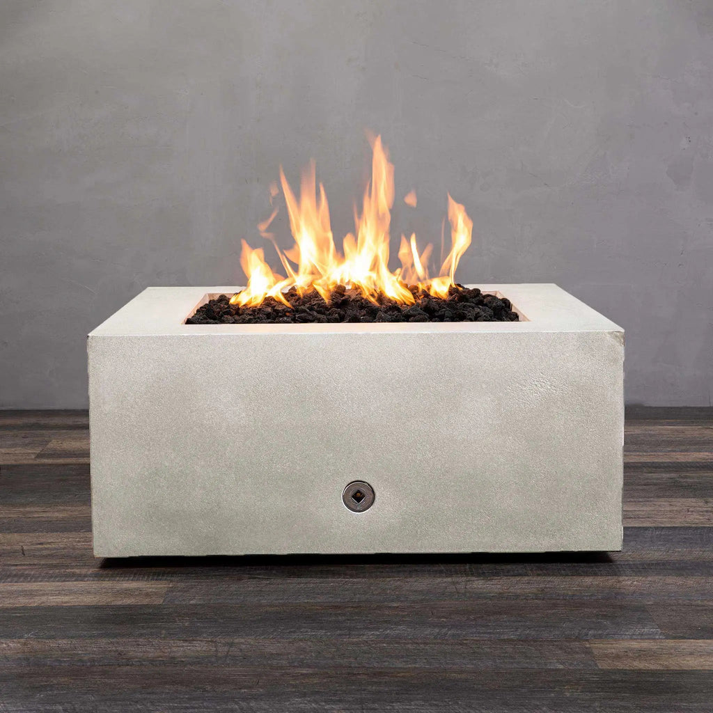 A front view of the Starfire Designs Gravity 36" Square Concrete Gas Fire Pit in white, featuring a robust flame rising from the fire pit’s lava rock fill. The sleek, modern concrete design complements outdoor spaces and is perfect for both residential and commercial use