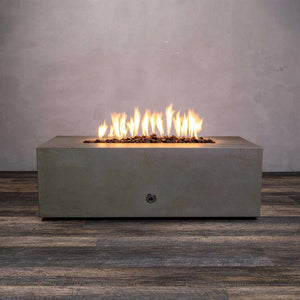 A front view of the Starfire Designs Gravity 48" x 32" Rectangle Concrete Gas Fire Pit in brown, showcasing a vibrant flame on top of brown lava rocks. This modern outdoor fire pit is crafted from durable concrete, designed to complement any patio space, and features a sleek rectangular structure with a minimalist design. Perfect for residential or commercial use, it enhances outdoor ambiance with its rustic brown finish