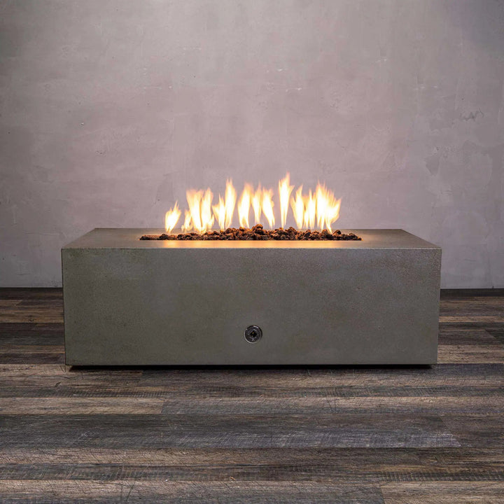A front view of the Starfire Designs Gravity 48" x 32" Rectangle Concrete Gas Fire Pit in brown, showcasing a vibrant flame on top of brown lava rocks. This modern outdoor fire pit is crafted from durable concrete, designed to complement any patio space, and features a sleek rectangular structure with a minimalist design. Perfect for residential or commercial use, it enhances outdoor ambiance with its rustic brown finish