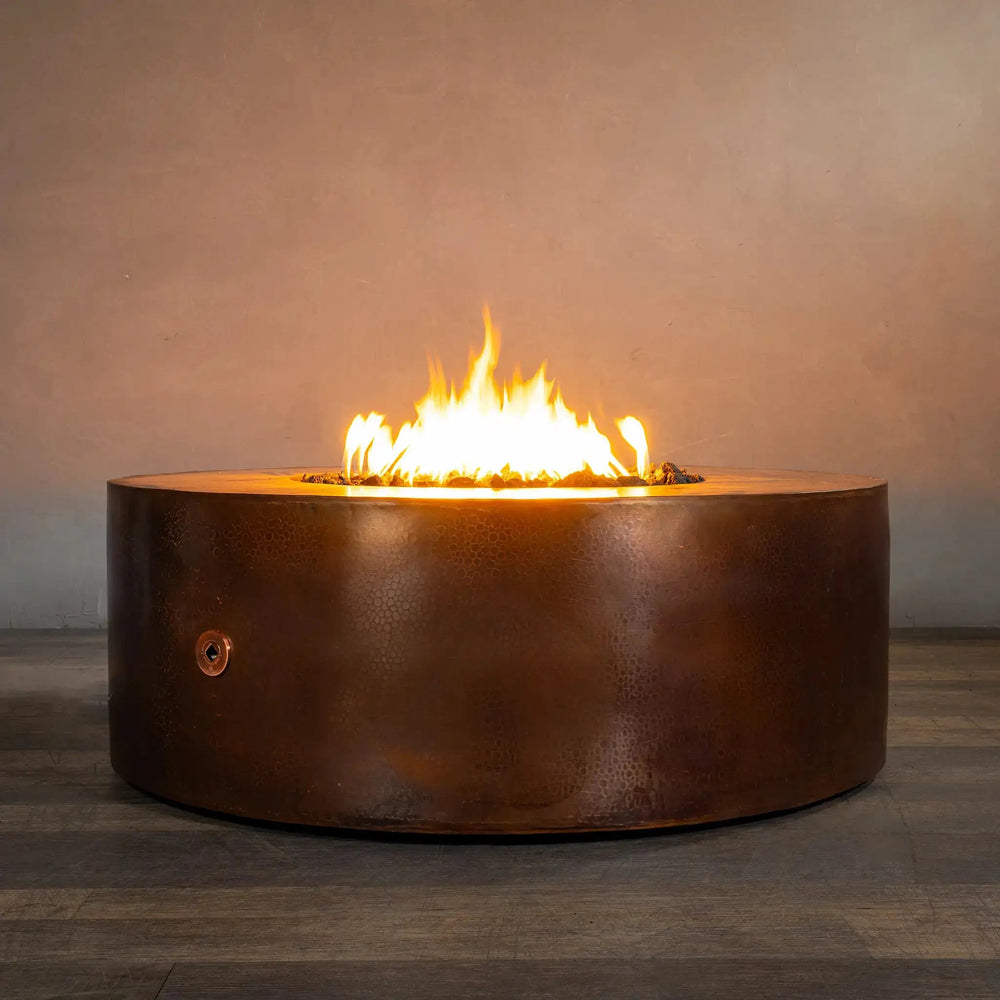 45-inch Gravity Moreno round copper fire pit by Starfire Designs, with flames glowing warmly, set against a neutral indoor background, emphasizing the luxurious design and ambiance it brings to any space