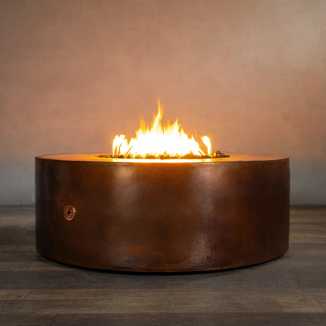 45-inch Gravity Moreno round copper fire pit by Starfire Designs, with flames glowing warmly, set against a neutral indoor background, emphasizing the luxurious design and ambiance it brings to any space