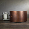 Side view of the Gravity Moreno 45-inch round copper fire pit by Starfire Designs with the propane tank drawer pulled out, showcasing the ease of access for refueling and the sturdy, handcrafted copper finish