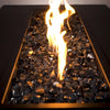 Close-up of Starfire 1/2" Broken Fire Glass in Black Reflective finish, illuminated by flickering flames. This premium fire glass adds depth and contrast to outdoor gas fire pits.