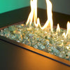 Starfire Glass 1/2" Broken Evergreen Reflective Fire Glass (10lbs) inside a gas fire table, radiating an eye-catching green shimmer. The premium-quality tempered glass enhances patio fire pits, fire pit bowls, and large backyard fire pits.